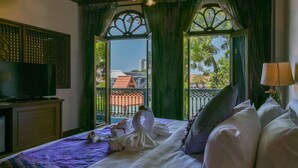 A hotel room with a bed, a television, a balcony with a view of buildings, and a decorative window frame. - 5 Heeren (Malacca City)