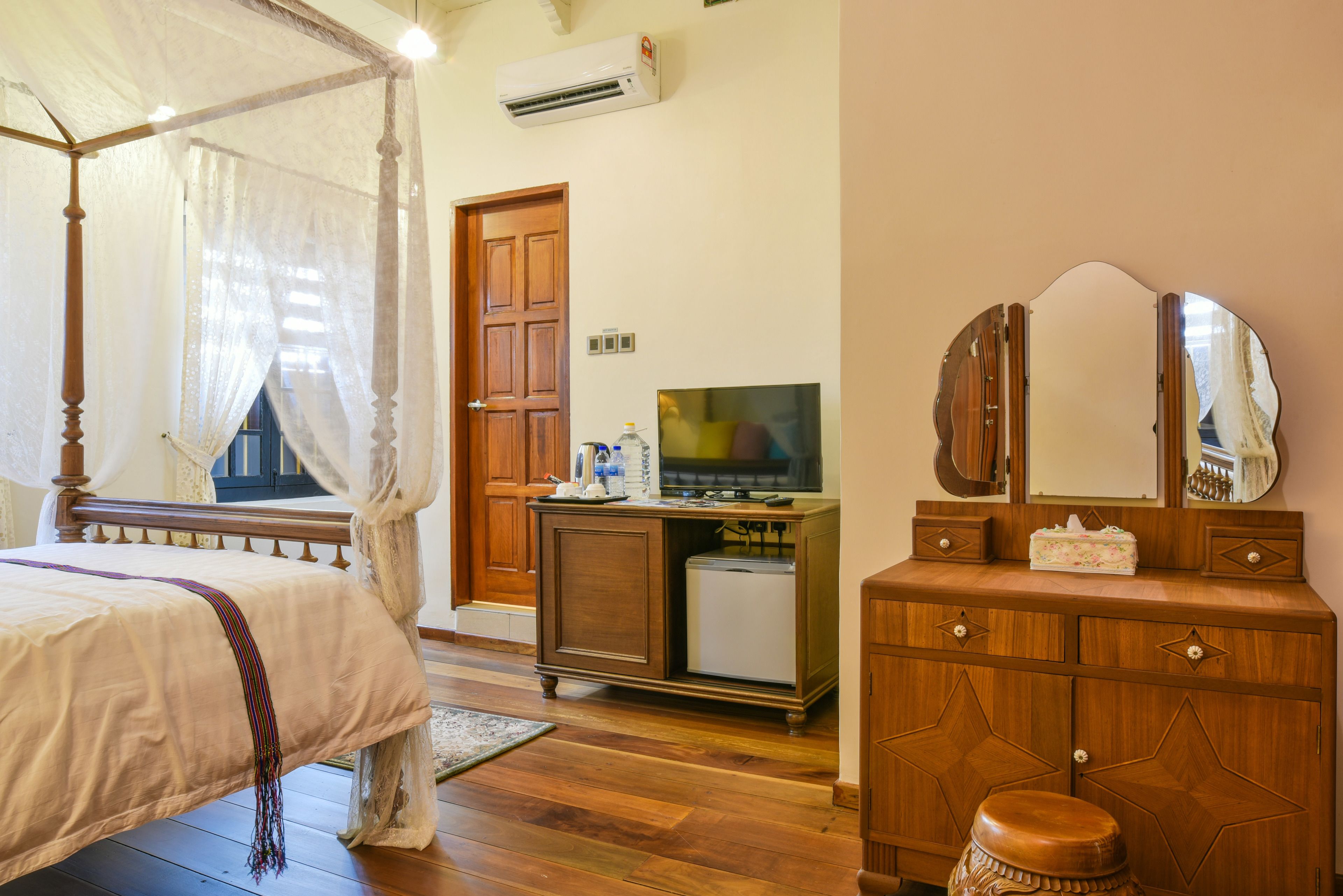 Une chambre à coucher avec un lit à baldaquin, une télévision, une commode et un miroir.