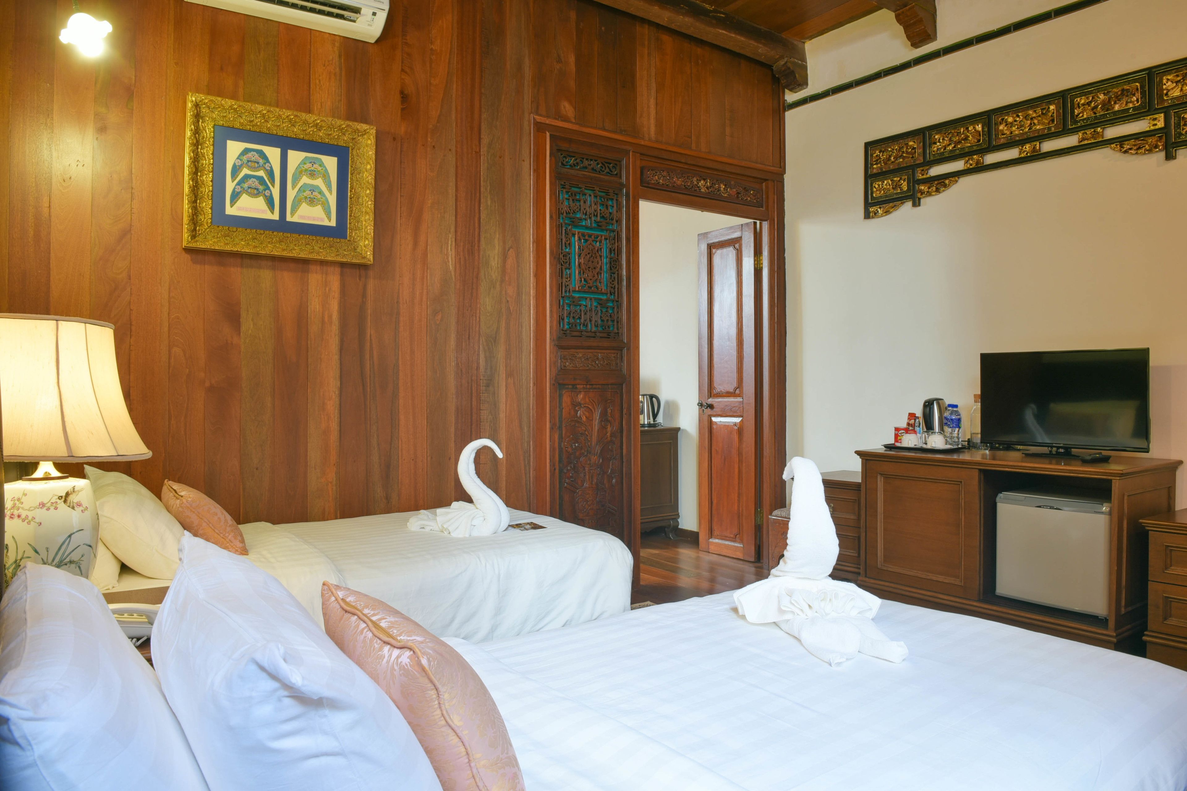 Habitación de hotel con dos camas, televisión, escritorio con computadora y puerta decorativa.