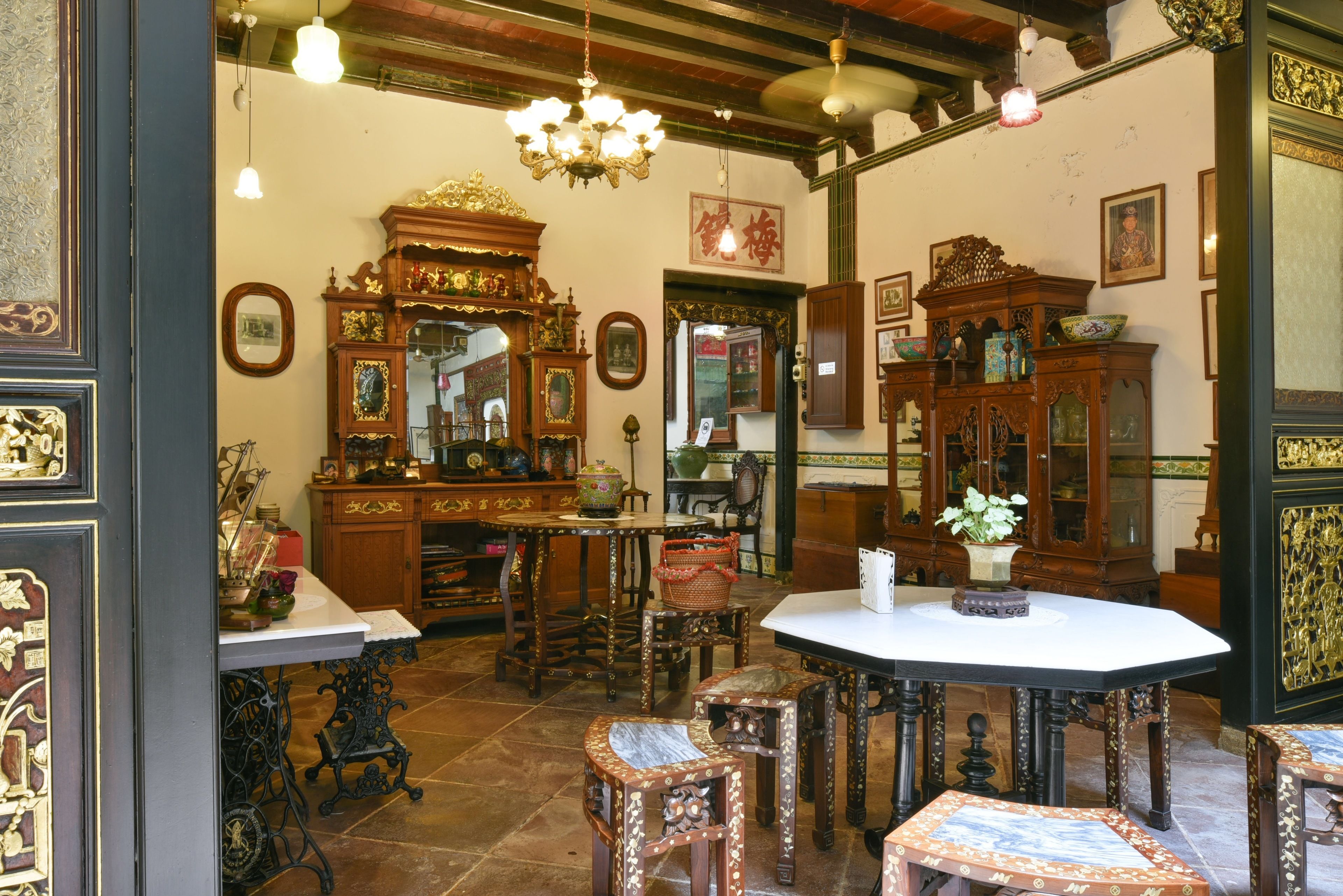 A traditional room with ornate wooden furniture, a white table, and a chandelier.