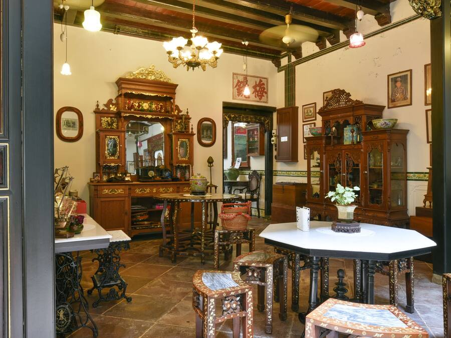 A traditional room with ornate wooden furniture, a white table, and a chandelier.