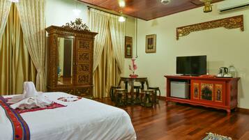A hotel room with a bed, a TV, a wooden cabinet, and a table with chairs.