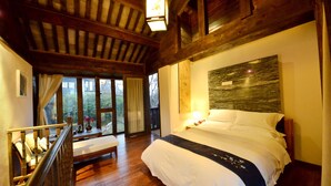 A bedroom with a wooden ceiling, a large bed, a nightstand, and a window with curtains.