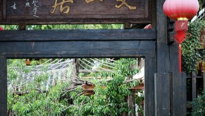 A traditional wooden entrance with a sign, a dog, and a red lantern.