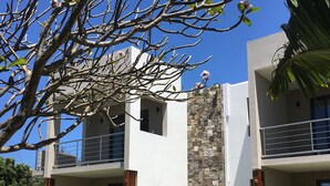 A modern two-story building with a stone facade, balconies, and a well-maintained lawn. - Valmarin Seafront Apartments (Trou d'Eau Douce)