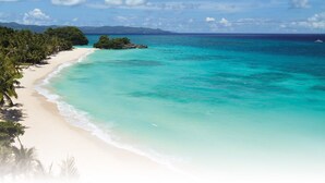 A beach with clear turquoise waters, white sand, and dense palm trees. - Valmarin Seafront Apartments (Trou d'Eau Douce)