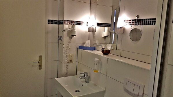 Un baño con lavabo, espejo, toallero y secador de pelo.