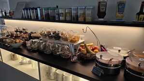 Een buffet met verschillende soorten eten en bijbehorende sauzen.