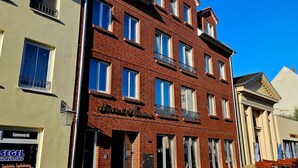 Een hotel met meerdere verdiepingen, een rode bakstenen gevel, diverse balkons en een bord waarop staat dat het een hotel is.