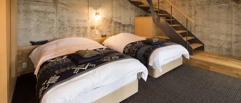 A modern bedroom with two beds, a wooden staircase, and a textured wall.