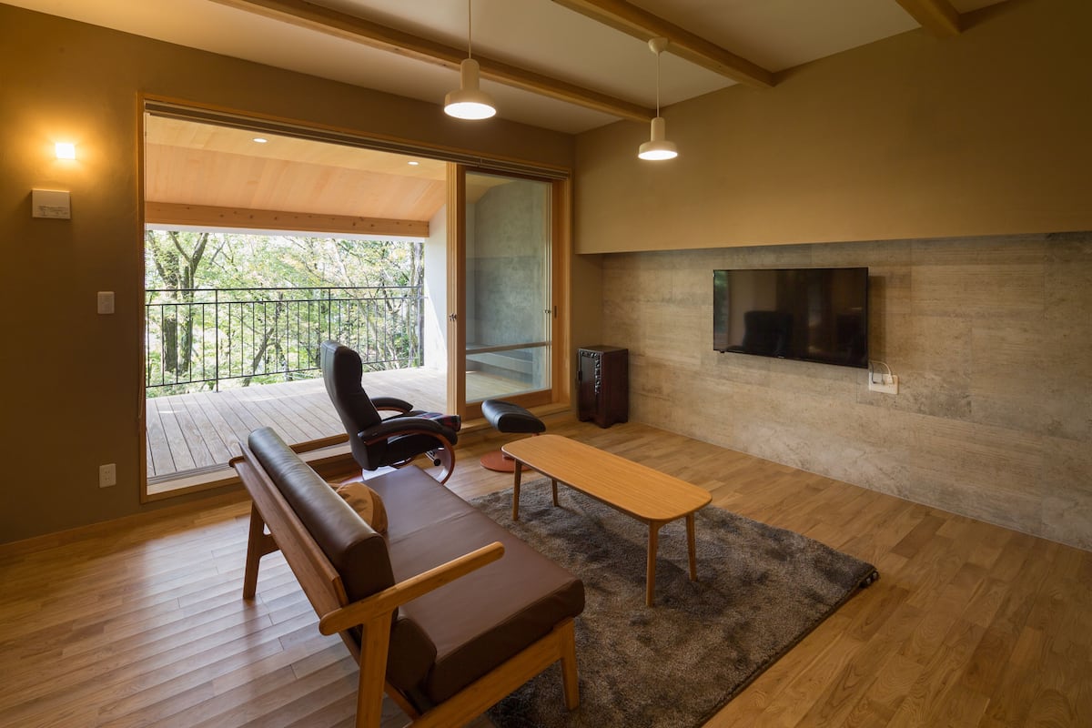 Un moderno salón con suelo de madera, un sofá, una mesa y un televisor instalado en la pared.