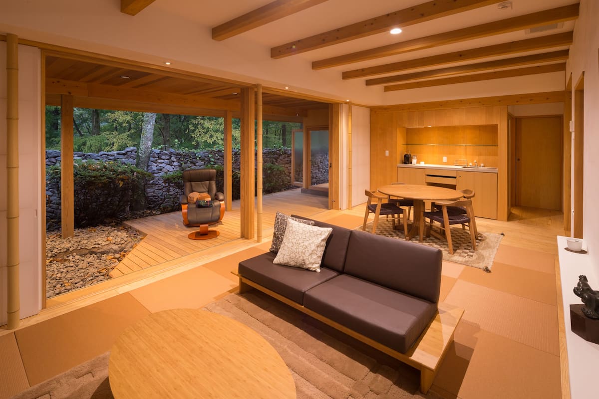 Un interior moderno con piso de madera, un sofá, una mesa de comedor y una zona de cocina.
