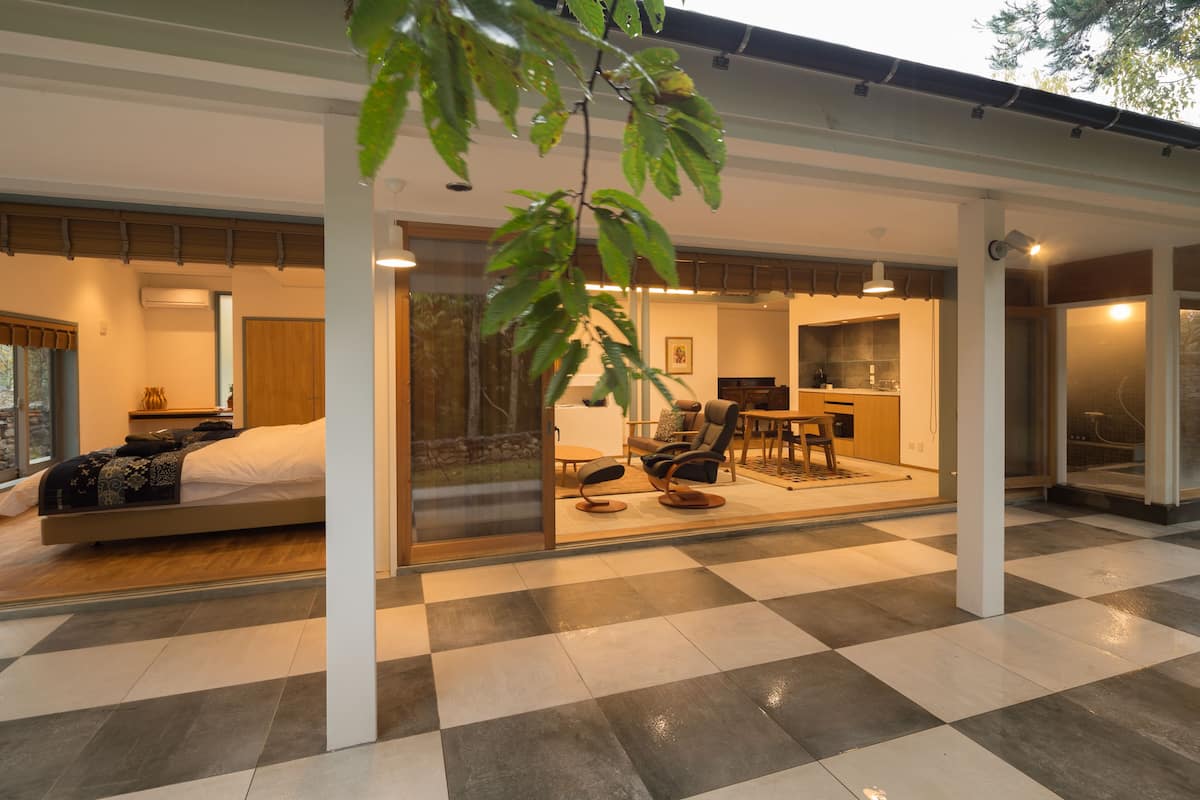 Un dormitorio moderno con una cama, una zona de estar con una silla y una mesa, y vistas a través de un ventanal.