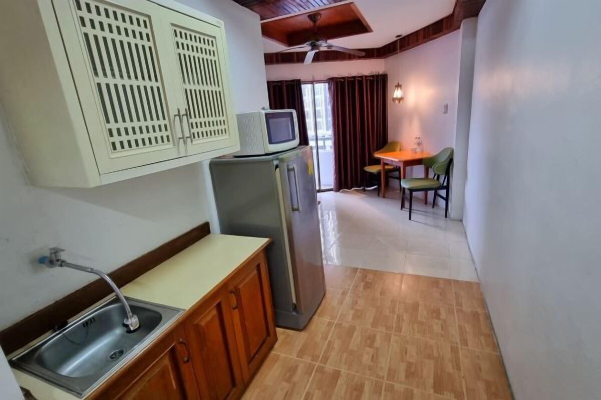 Una cocina compacta con un lavamanos, un microondas y un refrigerador. Hay un comedor con una mesa y sillas.
