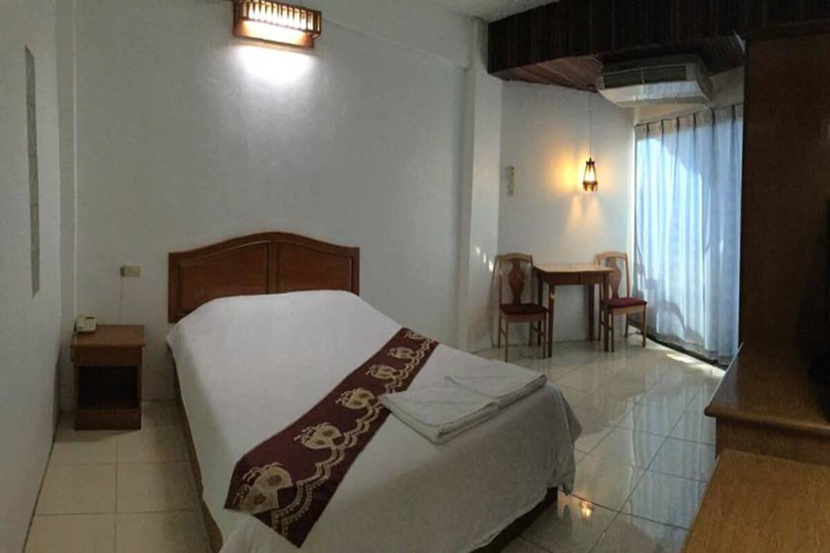 A hotel room with a bed, a nightstand, a desk, and a chair.