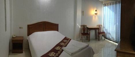 A hotel room with a bed, a nightstand, a desk, and a chair.