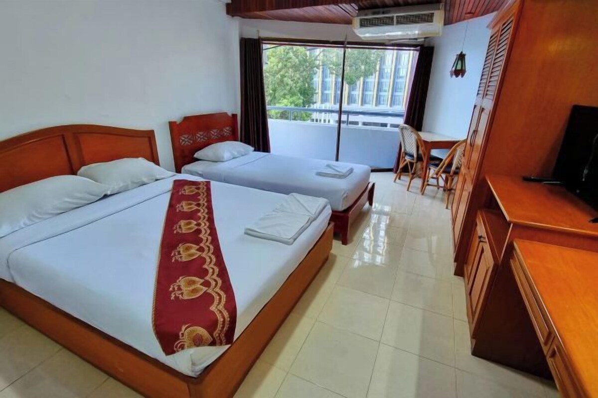 A hotel room with two beds, a desk, a chair, and a TV.