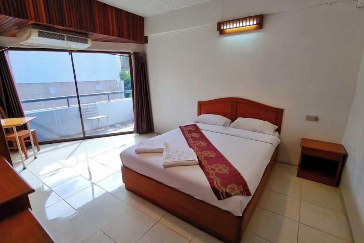A hotel room with a bed, a desk, and a view of the outside.