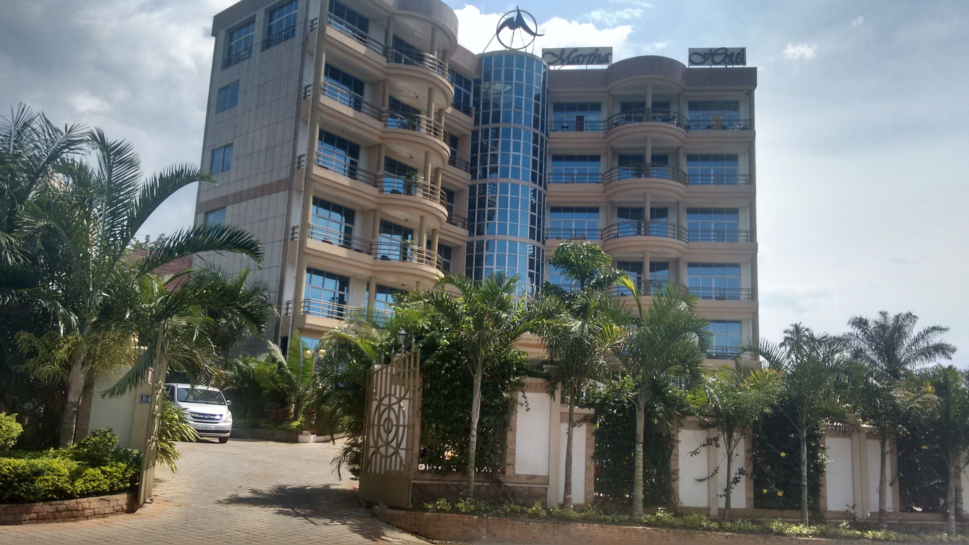 A multi-story hotel with a modern design, featuring balconies and a central cylindrical glass tower.