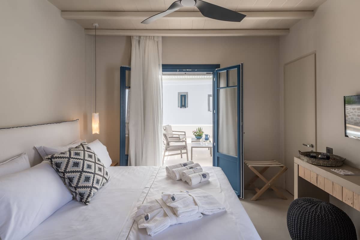 Ein Hotelzimmer mit Bett, Schreibtisch, Stuhl und Blick ins Freie.