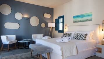A modern bedroom with a large bed, two chairs, a small table, and a bench.