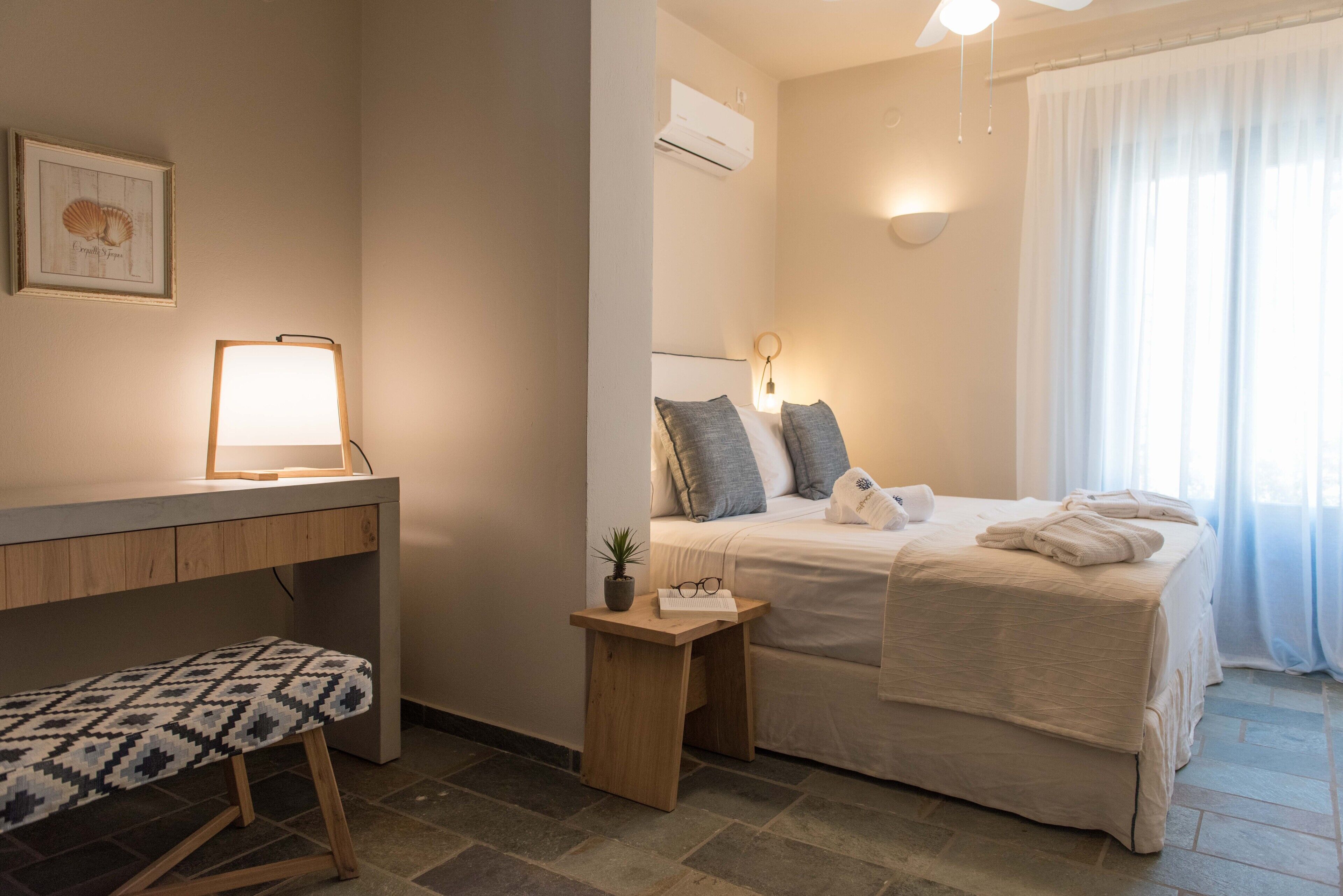 Una camera da letto con un letto, un comodino, una lampada e una piccola pianta in vaso.