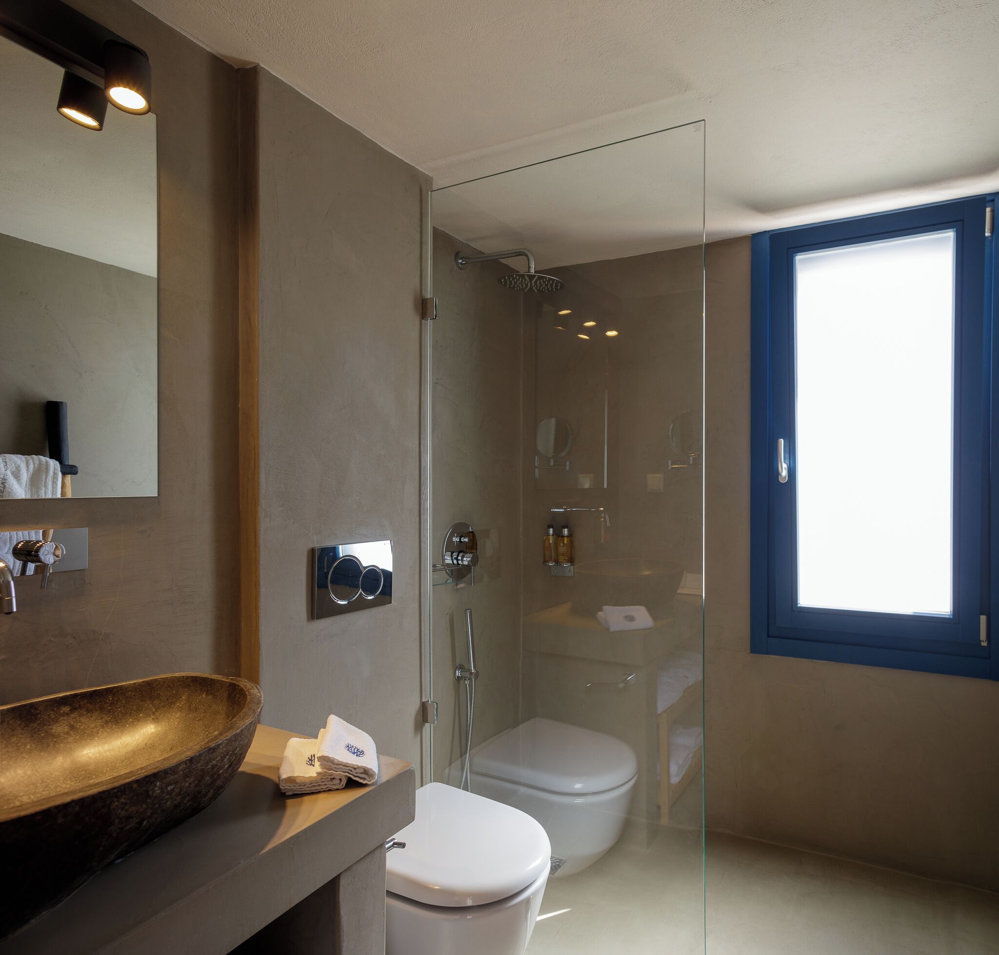 Une salle de bain moderne avec une douche à parois de verre, un grand lavabo sur pied et des toilettes.