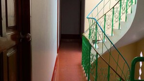 A hallway with a wooden door on the left and a green metal staircase on the right. - Bliss Mansion (Pattaya)