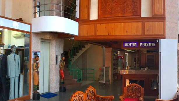 A lobby with a reception desk, a staircase, and wooden furniture. - Bliss Mansion (Pattaya)