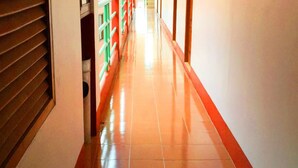 A corridor with a shiny tiled floor, a red border, and a green railing. - Bliss Mansion (Pattaya)