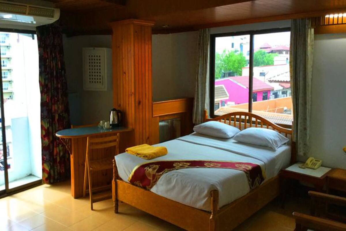 A room with a bed, a desk, a chair, and a window with a view of buildings.