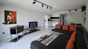 A modern living room with a sofa, coffee table, TV, and a kitchen area with a dining table. - Yahsi's Yahsi Resort Aparts (Bodrum)