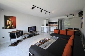 A modern living room with a sofa, coffee table, TV, and a kitchen area with a dining table. - Yahsi's Yahsi Resort Aparts (Bodrum)