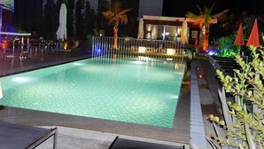 A nighttime swimming pool area with a fence, palm trees, and outdoor seating. - Yahsi's Yahsi Resort Aparts (Bodrum)