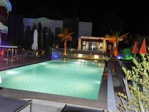 A nighttime swimming pool area with a fence, palm trees, and outdoor seating. - Yahsi's Yahsi Resort Aparts (Bodrum)