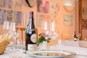 A table set with wine glasses, a bottle of Amaro della Valpolicella, and a basket of bread. - Hotel Ristorante Sasso (Bovolone)