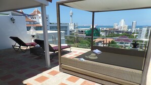 A balcony with two lounge chairs, a small table, and a view of a cityscape including a tower. - Westbury Residence (Pattaya)
