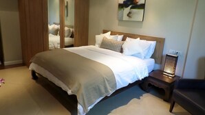 A bedroom with a bed, a nightstand, a wardrobe, and a painting on the wall. - Westbury Residence (Pattaya)