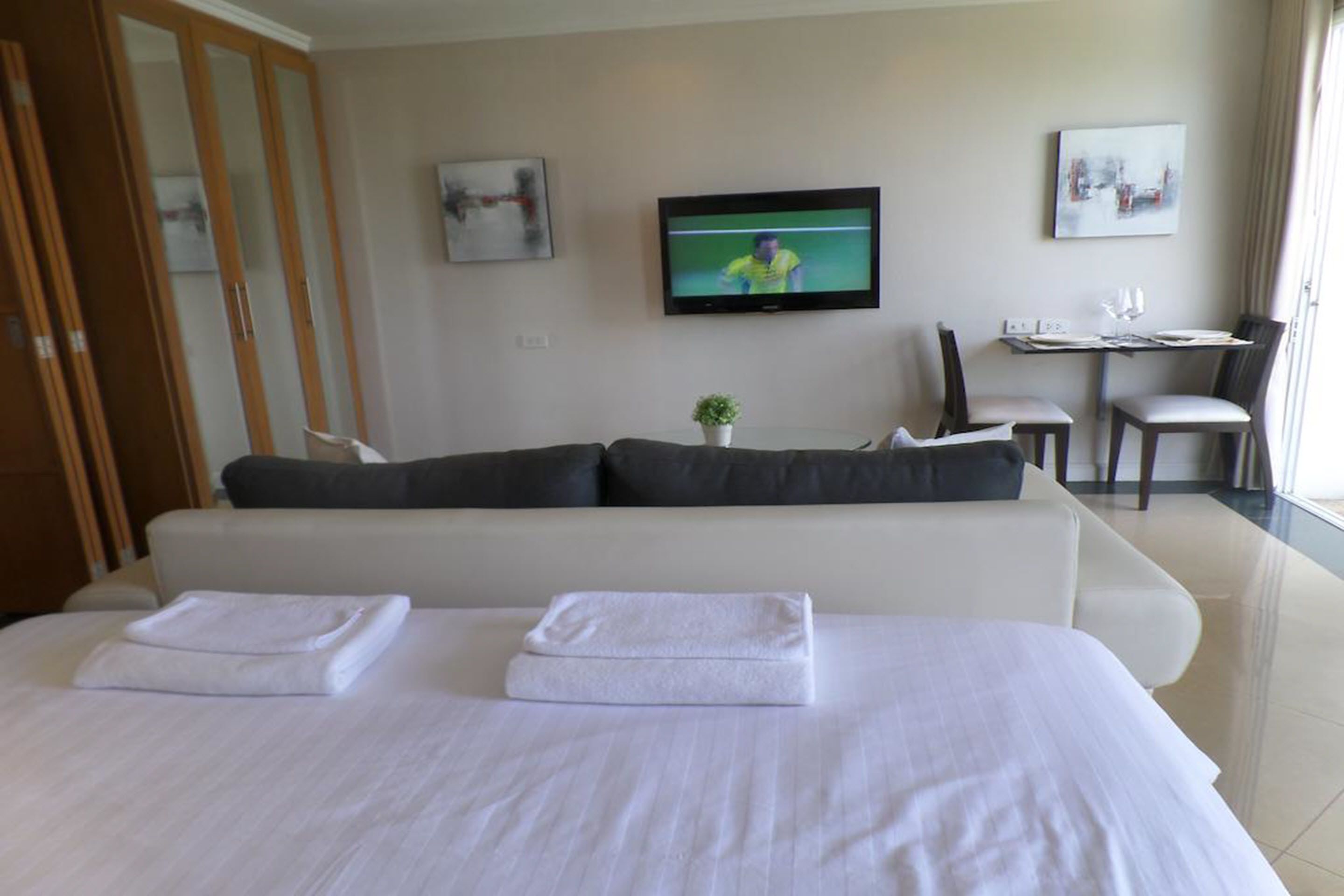 Une chambre d’hôtel avec un grand lit, un canapé, une télévision et un coin repas.