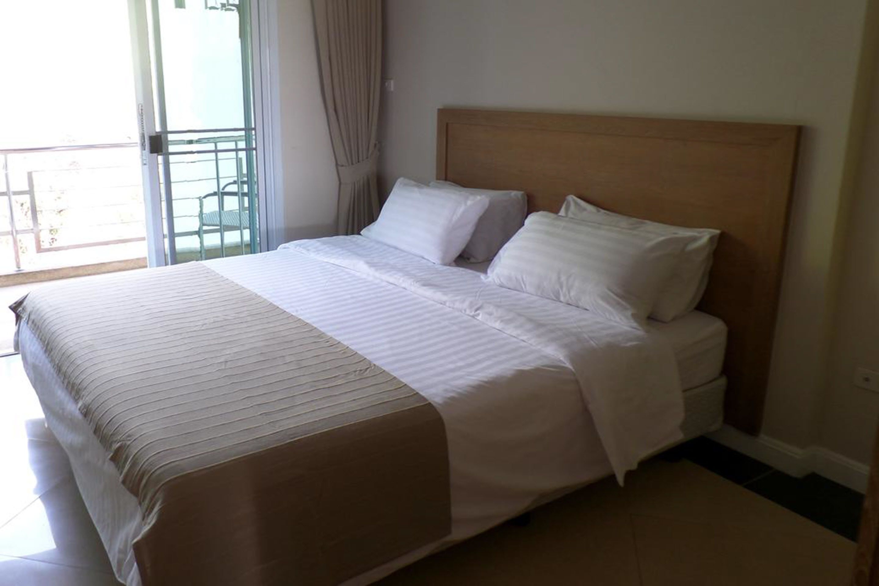 Una cama bien hecha con sábanas blancas en una habitación con cabecera de madera.