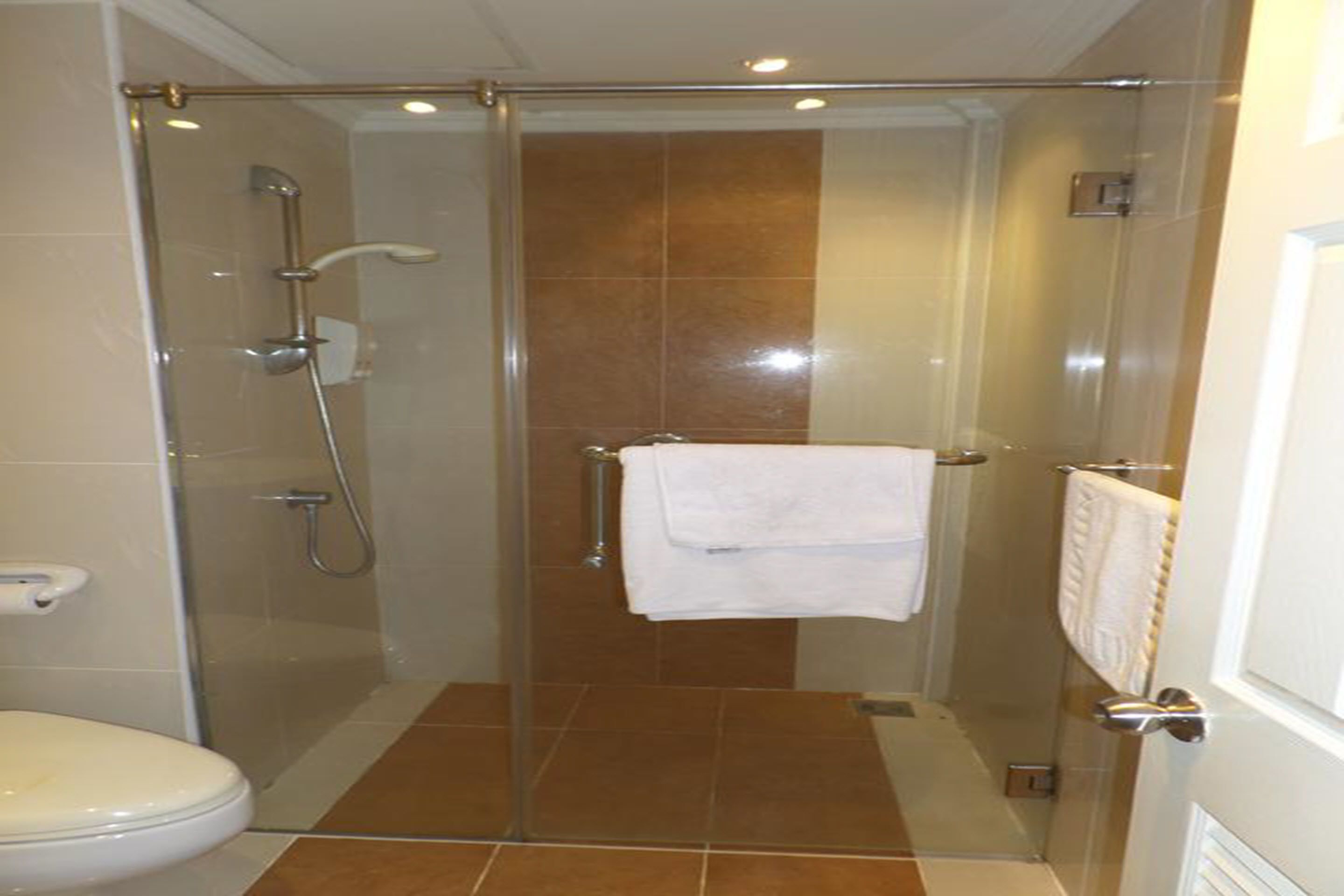 A glass-enclosed shower stall with a white towel hanging on the wall.