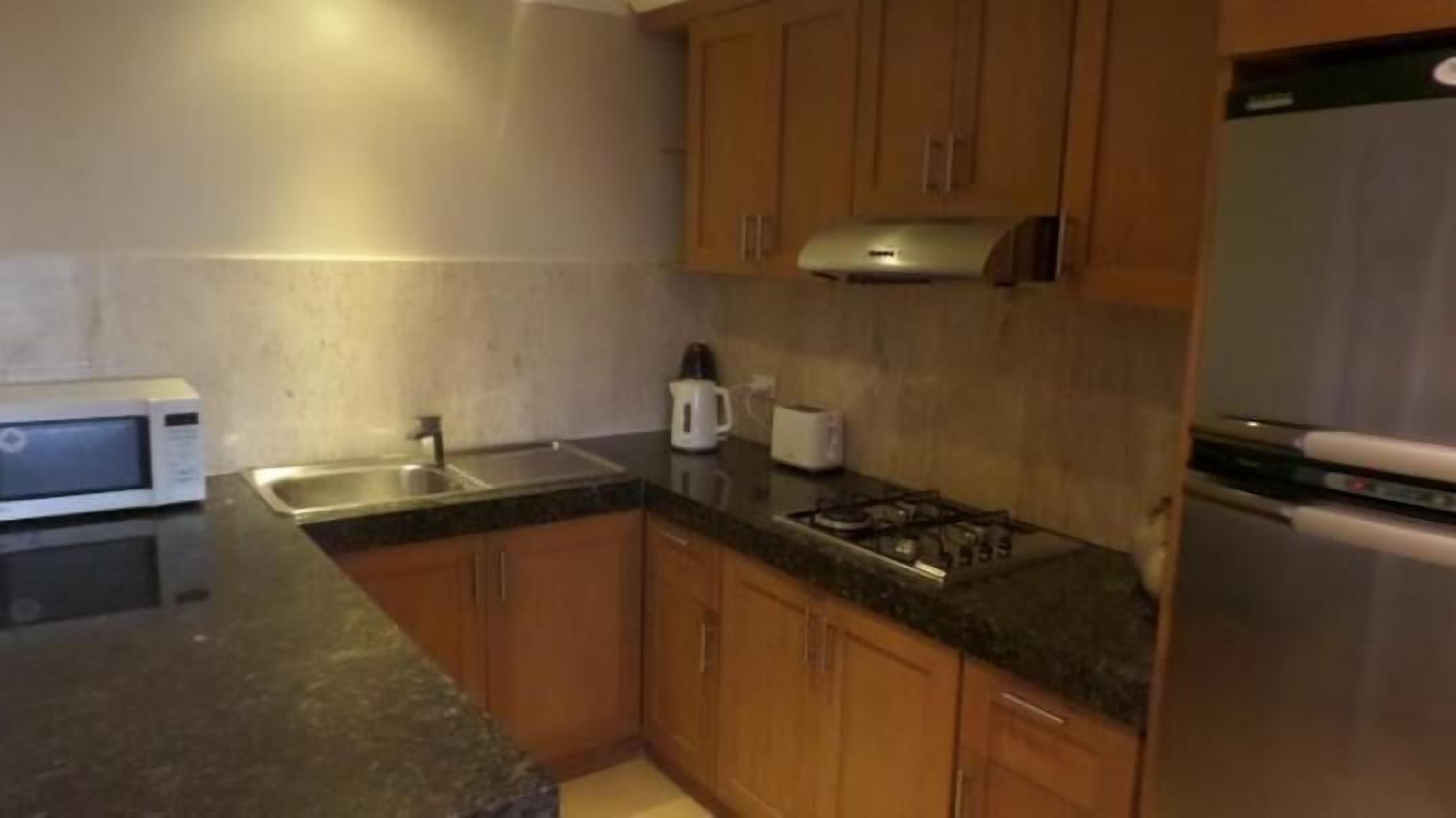 A kitchen with wooden cabinets, a microwave, a toaster, and a stove.