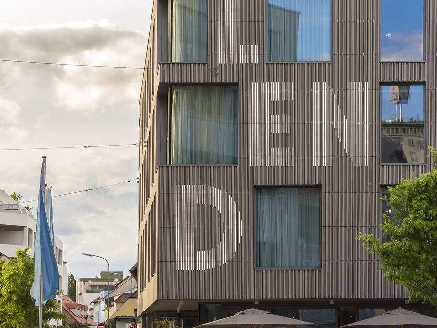 A modern building with a unique facade design, outdoor seating area, and a visible entrance.
