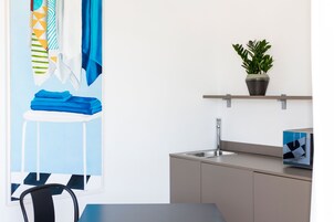Una cocina moderna con un lavamanos, una planta en maceta y una silla azul.