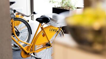 A yellow bicycle with a basket and a seat, parked near a building with a sign that reads "LEND HOTEL".