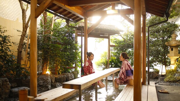 A traditional Japanese onsen with wooden benches and stone surroundings. - Dogo Prince Hotel (Matsuyama)