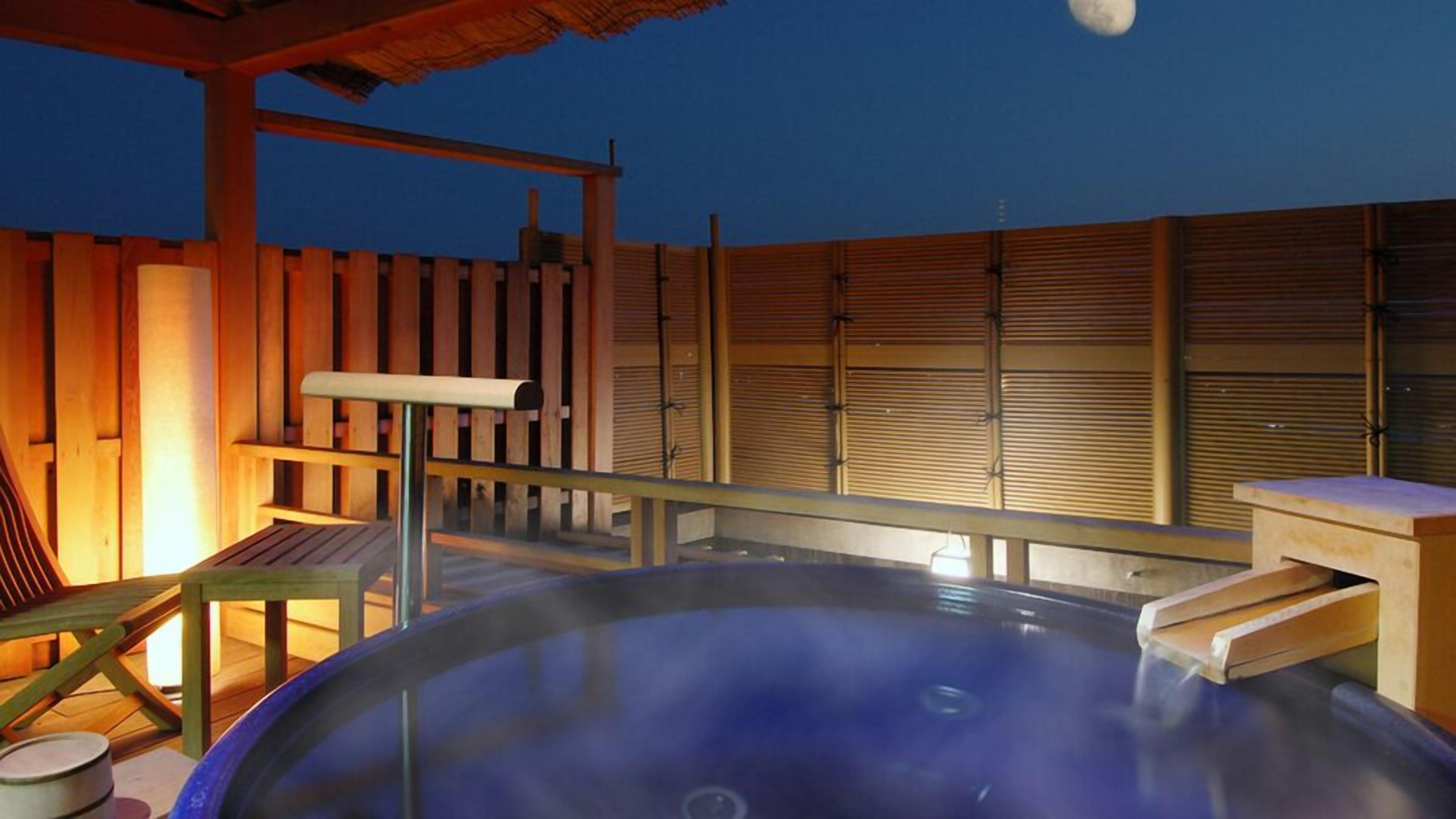 Un bain à remous avec une terrasse en bois et une clôture en bois en arrière-plan.