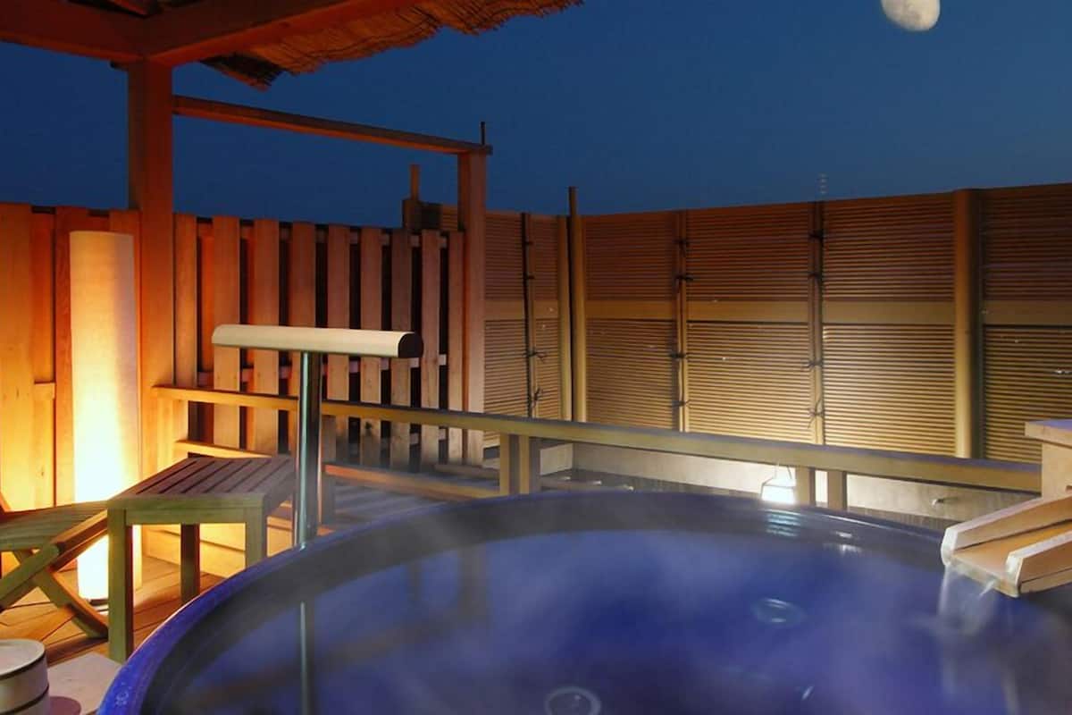 A hot tub with a wooden deck and a wooden fence in the background.