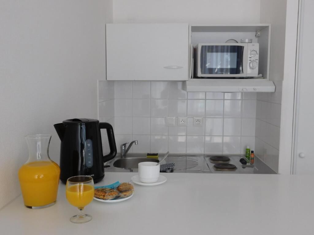 A modern kitchen with a microwave, kettle, and sink.