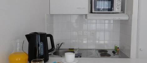 A modern kitchen with a microwave, kettle, and sink.
